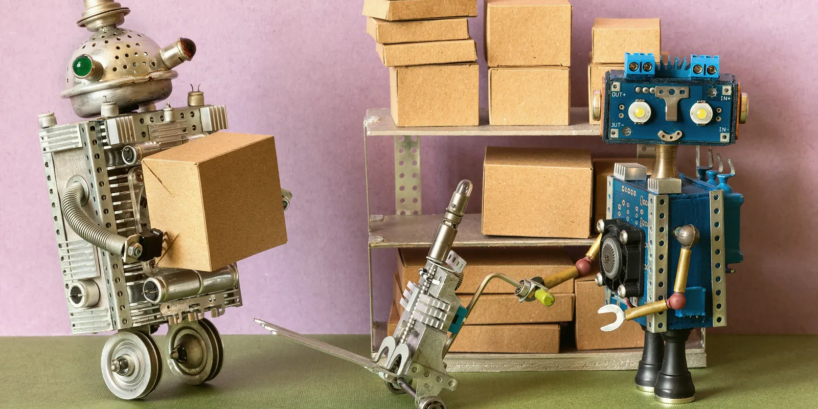 Dwa roboty przy regale z paczkami-modułami — składasz system z tego, czego potrzebujesz