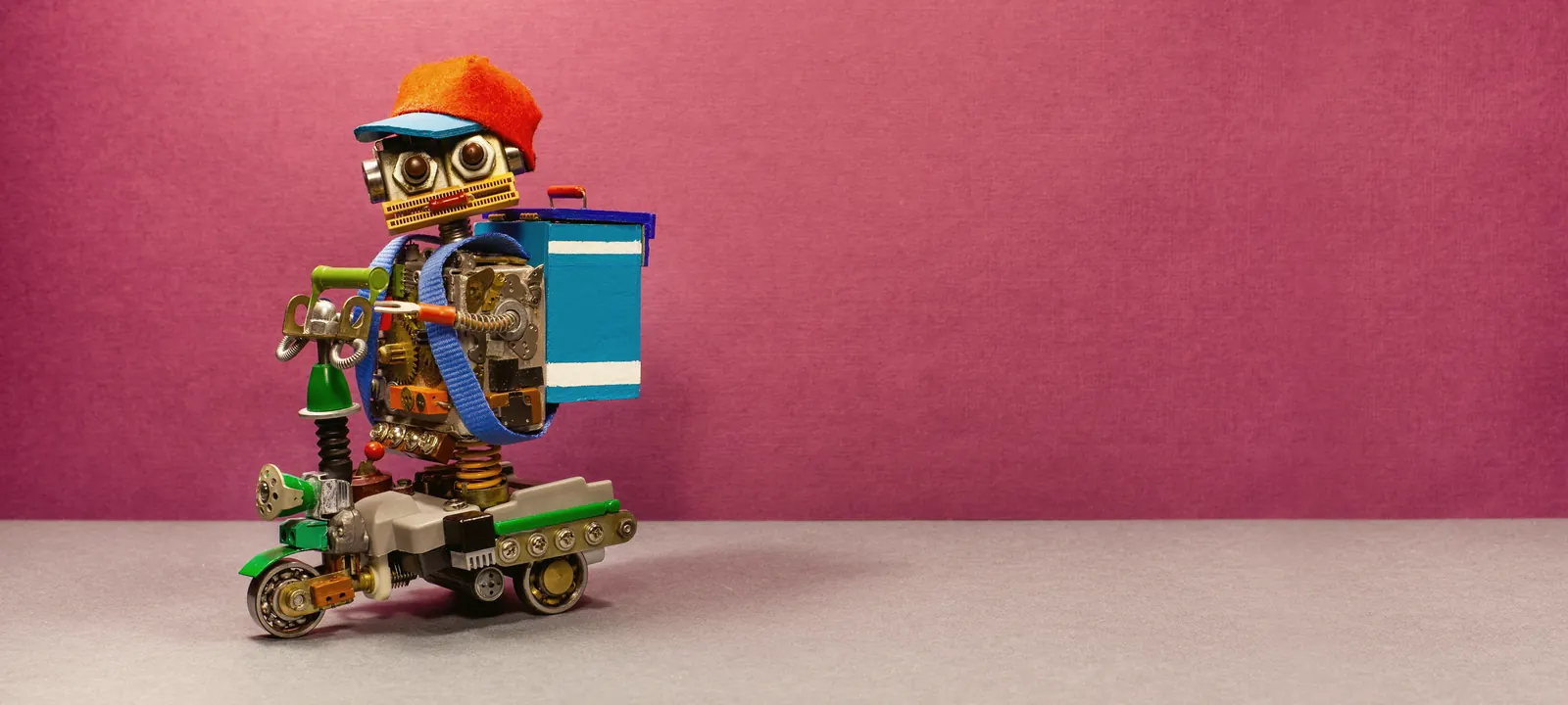 Robot-kurier w czapce, na skuterze z torbą dostawczą — zamówienie już w drodze