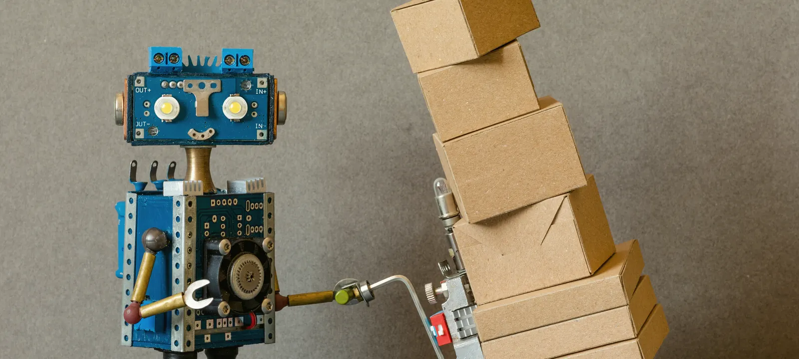 Robot wiozący na wózku transportowym chwiejący się stos paczek