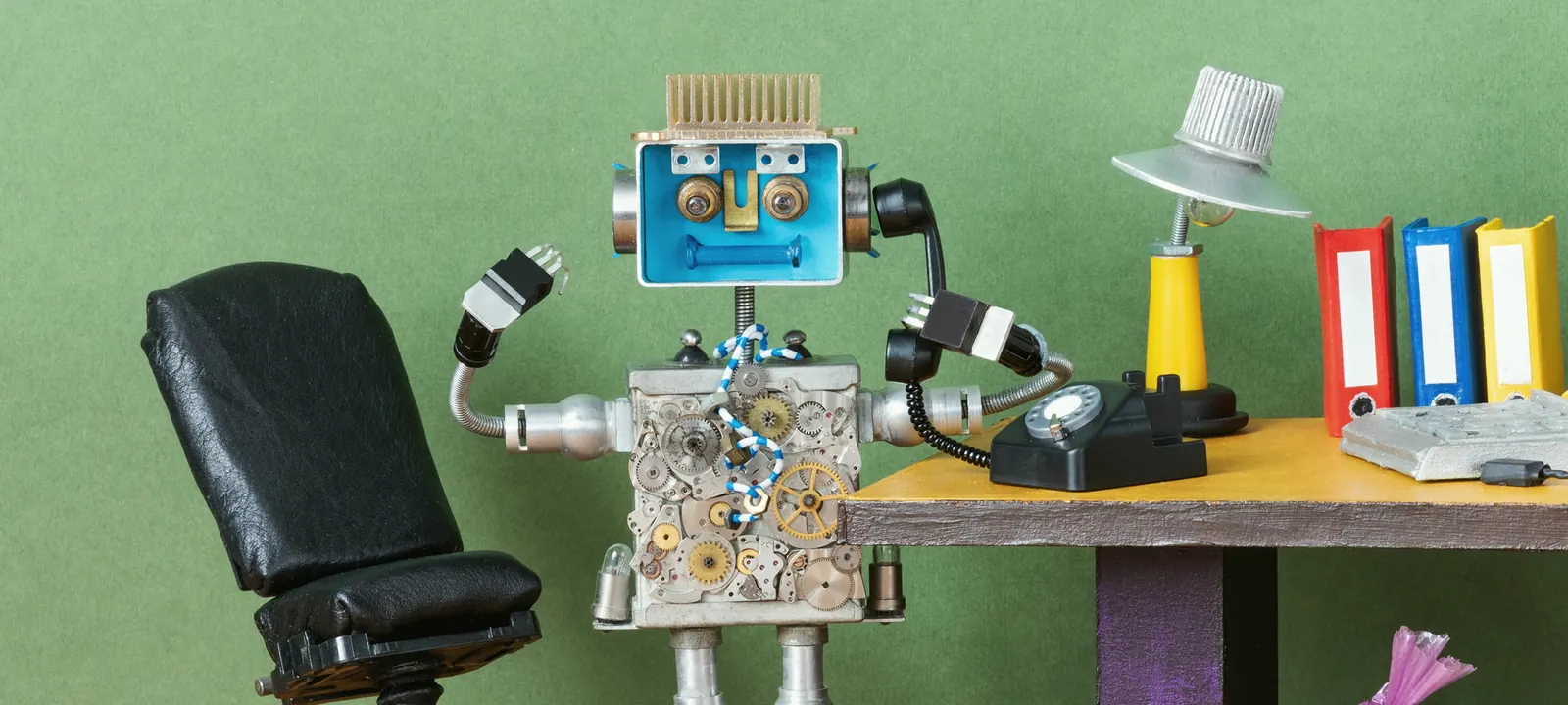 Robot przy biurku z segregatorami i telefonem — porządek i dokumentacja od pierwszego dnia wdrożenia